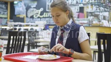 穿着校服的少女坐在<strong>学校食堂</strong>的桌子旁吃东西。